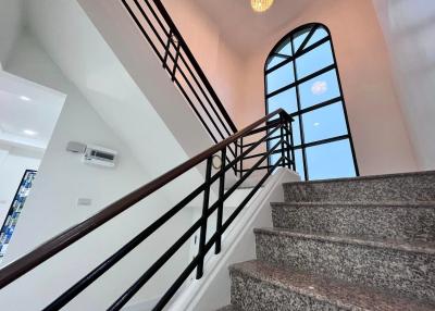 Elegant staircase with wrought iron railing and arched window