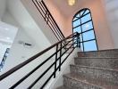 Elegant staircase with wrought iron railing and arched window