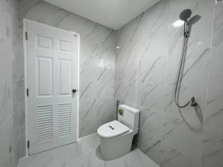 Modern bathroom with white tile walls and floors, shower, and toilet