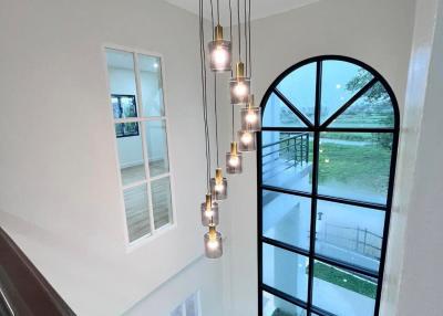 Elegant staircase with cascading pendant lights and large arched window
