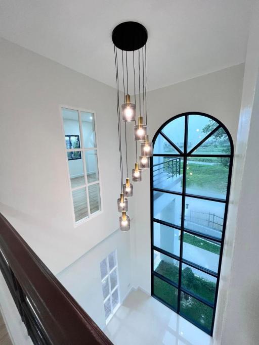 Elegant staircase with cascading pendant lights and large arched window