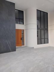 Spacious and modern building entrance with large windows and wooden door
