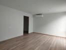 Spacious and bright unfurnished living room with hardwood floors and air conditioning unit