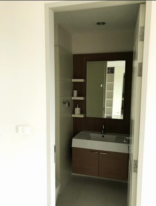 Modern bathroom with a wall-mounted sink, vanity, and mirrored medicine cabinet