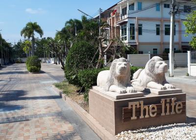 Elegant entrance of a residential community with lion statues and palm trees