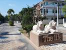 Elegant entrance of a residential community with lion statues and palm trees