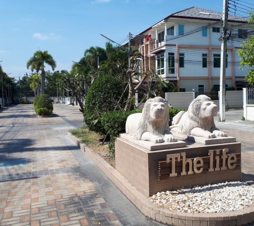 Elegant entrance of a residential community with lion statues and palm trees