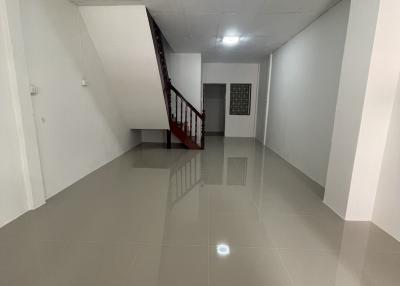 Spacious hallway with glossy tiled flooring and staircase with wood railing