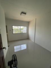 Bright empty bedroom with glossy tiled flooring and a large window