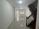 Bright hallway with glossy tiled floor and wooden staircase