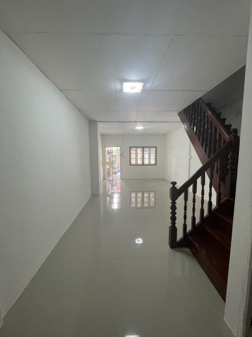 Bright hallway with glossy tiled floor and wooden staircase