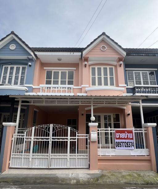 Two-story residential house with pink facade and security gate