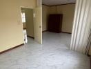 Spacious empty room with marble flooring and large windows with curtains