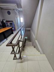 Modern staircase with wooden railing and ceramic floor tiles