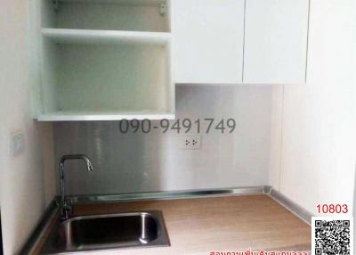 Compact kitchen space with stainless steel sink and wall-mounted shelving