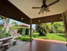 Spacious covered patio with ceiling fan and garden view
