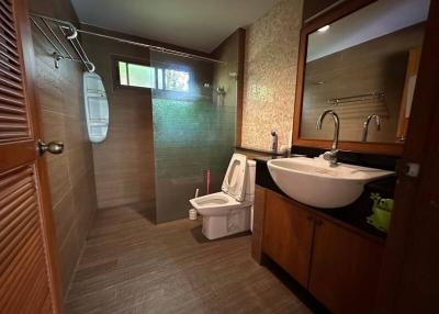 Modern bathroom with a glass shower area, wooden floor, and a vessel sink