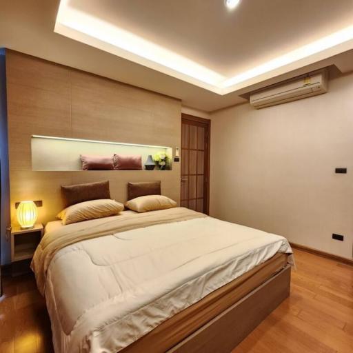 Modern bedroom with a large comfortable bed, warm lighting, and wood flooring