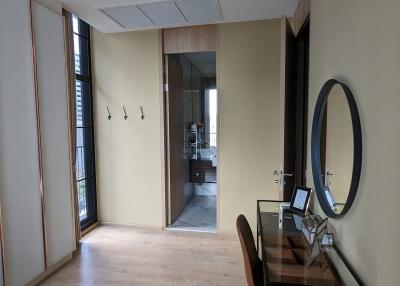 Cozy bedroom with a wooden floor, modern mirror, and a view into the hallway