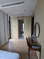 Cozy bedroom with a wooden floor, modern mirror, and a view into the hallway