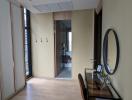 Cozy bedroom with a wooden floor, modern mirror, and a view into the hallway