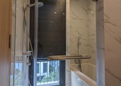 Modern bathroom with a glass shower stall and marble walls