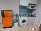 Compact modern kitchen with orange fridge and white appliances