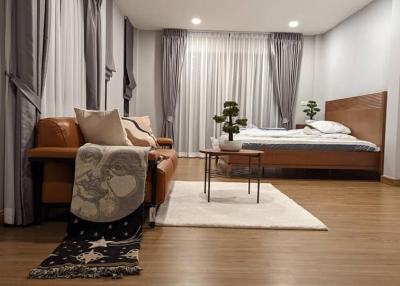 Modern bedroom interior with queen size bed, comfortable leather sofa, and decorative plants