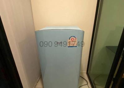 Compact blue refrigerator in a narrow utility space