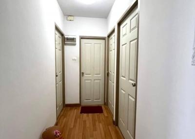 Well-lit hallway with wooden flooring and multiple doors
