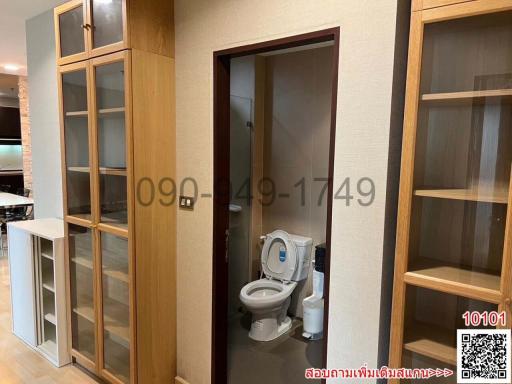 Modern bathroom viewed through an open door with visible toilet and wooden accents