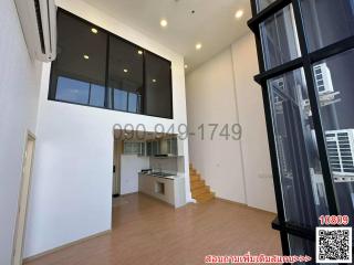 Spacious living area with high ceiling, modern kitchen, and staircase