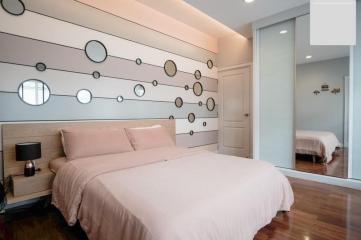 Contemporary bedroom with artistic wall design, hardwood floors, and large bed