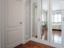 Modern hallway with reflective glass doors leading to a well-lit bedroom