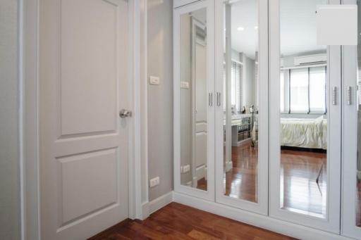 Modern hallway with reflective glass doors leading to a well-lit bedroom