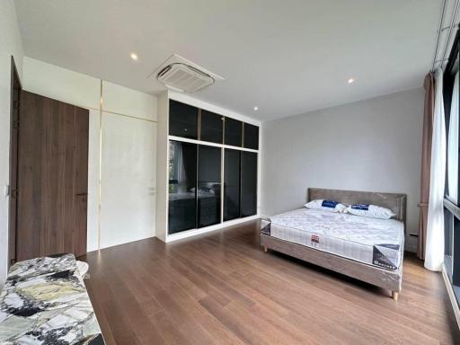 Spacious bedroom with wooden flooring and large windows