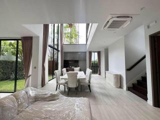 Spacious living room with high ceiling, large windows, and modern dining area