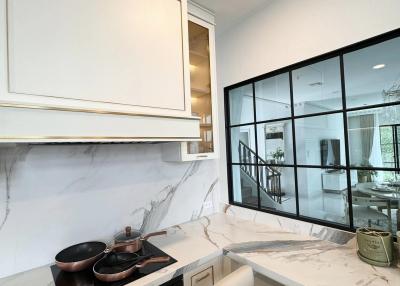 Modern kitchen interior with marble countertops and large window overlooking patio