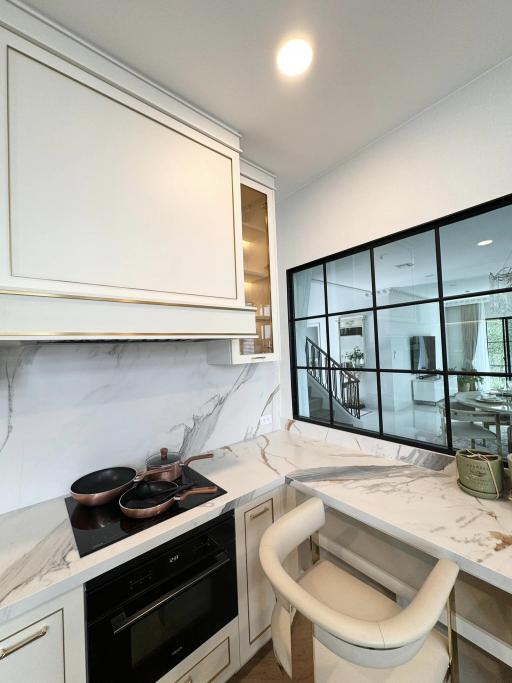 Modern kitchen interior with marble countertops and large window overlooking patio