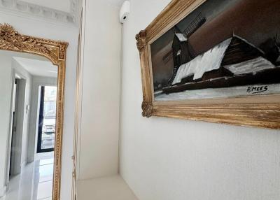Bright and narrow corridor with decorative framed painting and a mirror