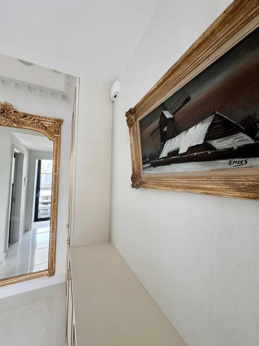 Bright and narrow corridor with decorative framed painting and a mirror