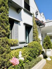 Elegant white house exterior with manicured garden and sculptures