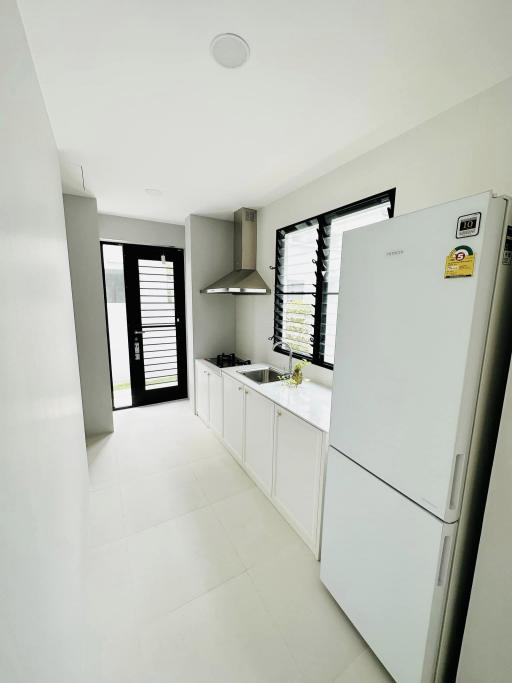 Modern white kitchen with stainless steel appliances and ample natural light