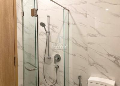 Modern bathroom with glass shower enclosure and marble walls