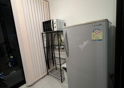 Compact kitchen corner with refrigerator and racks beside a glass door
