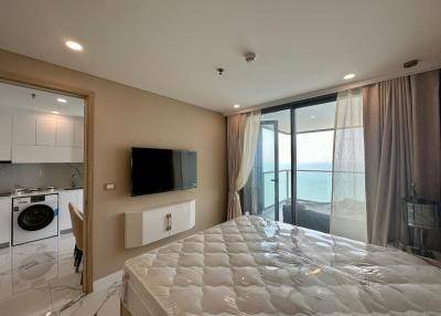 Studio apartment interior with kitchenette, bed, and sea view