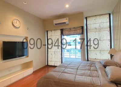 Spacious bedroom with a large bed, wall-mounted TV and balcony access