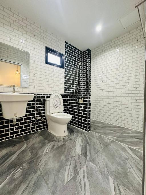 Modern bathroom with contrasting tiled walls, well-lit with a window