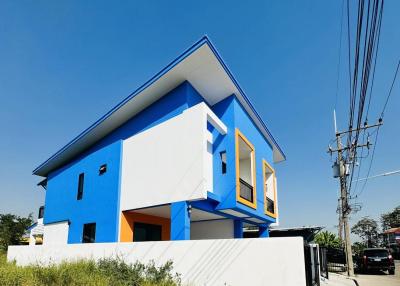 Modern two-story blue and white house with distinctive yellow windows and clear blue sky
