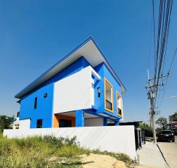 Modern two-story blue and white house with distinctive yellow windows and clear blue sky